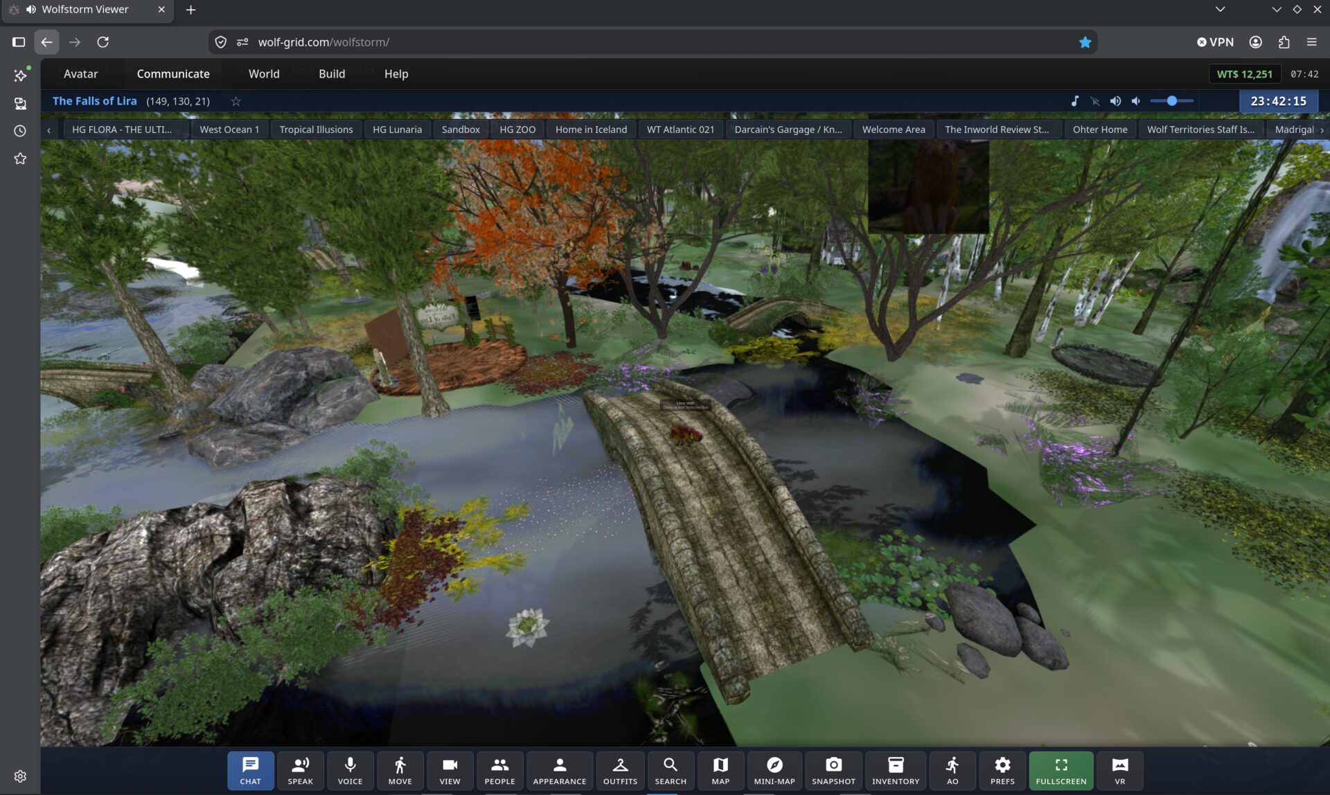 WolfStorm open in a Chrome tab at wolf-grid.com/wolfstorm. The region The Falls of Lira fills the window: a stone bridge crossing a river between autumn trees and mossy rocks. Menus for Avatar, Communicate, World, Build and Help run along the top, a row of saved region tabs sits beneath them, and a toolbar of chat, voice, movement, appearance, map, inventory, fullscreen and VR buttons runs along the bottom.